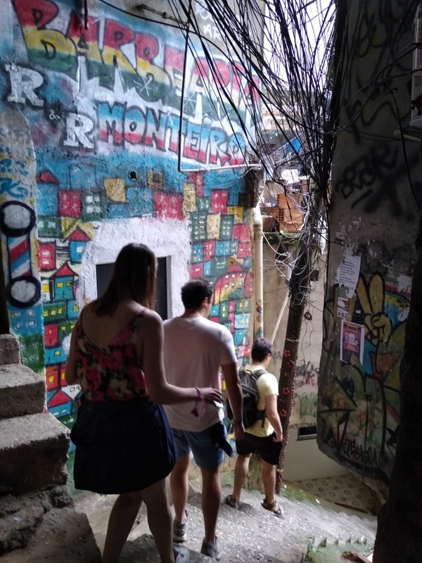 Three tourists going down a steep alleyway in Rocinha